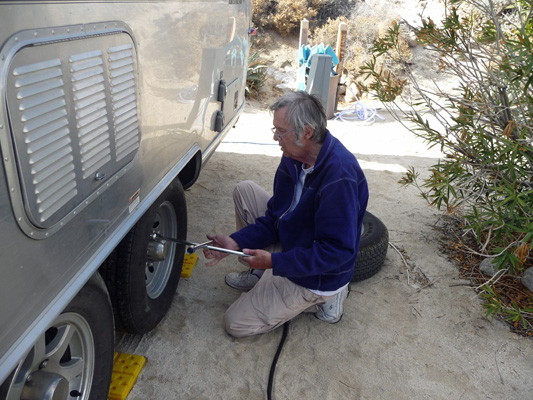 Walter Cooke putting lug nuts back on Airstream wheel