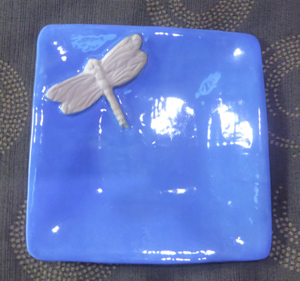a dragonfly in a blue jewelry bowl.